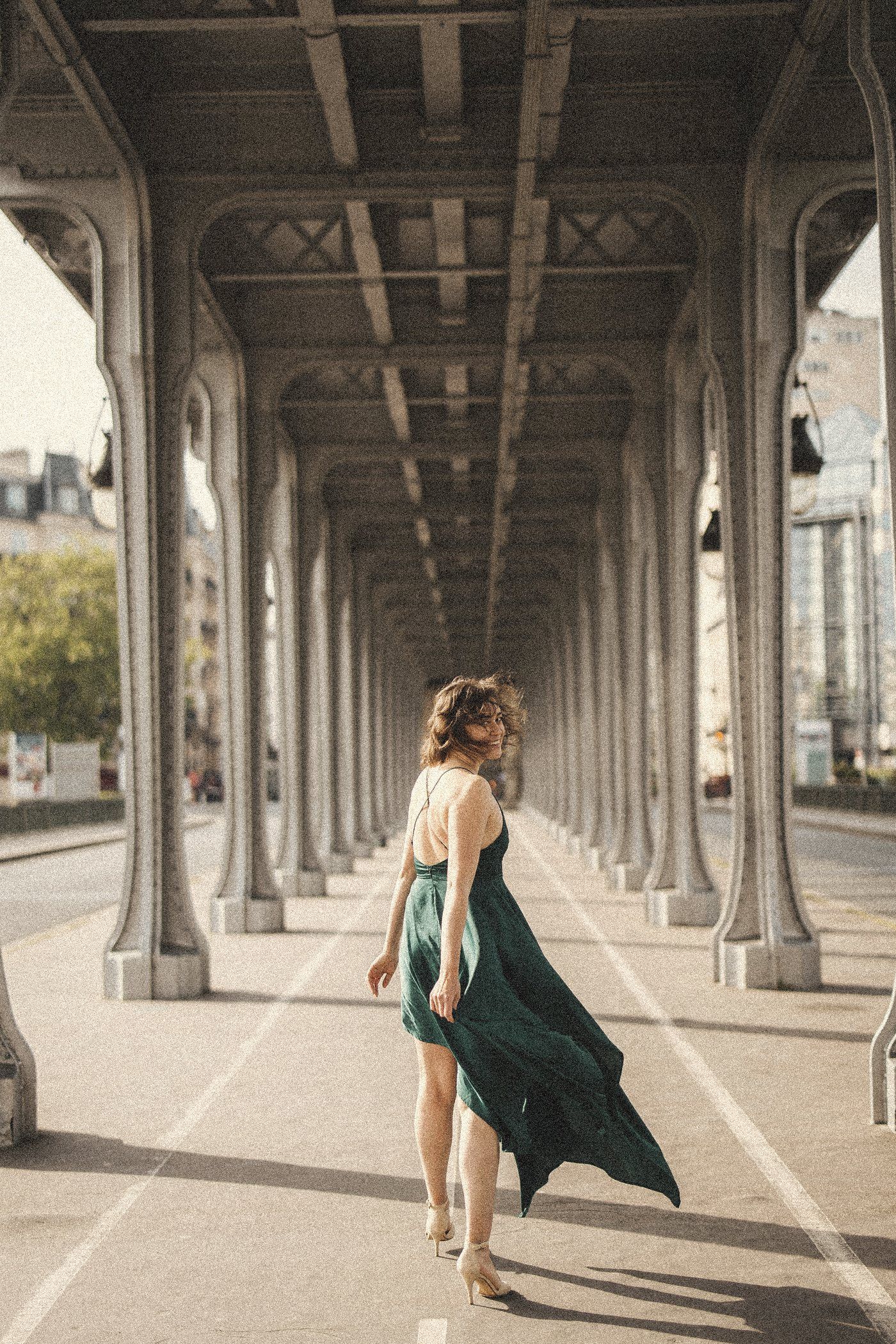 Aliya striding in a green dress under the Bir-Hakeim bridge